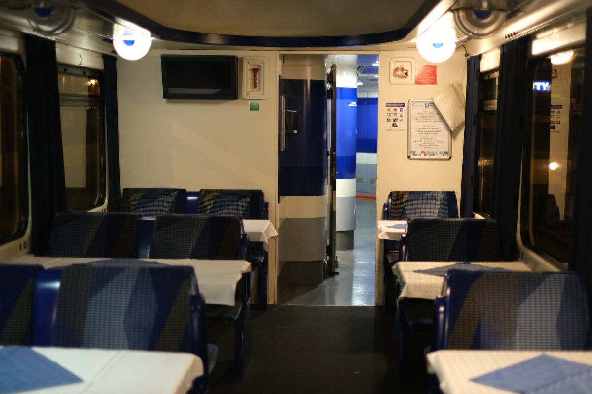 Picture of the inside of the dining car with Eurocity train "Hungaria" between Hamburg and Budapest. The colors blue and white are dominating. The tables have a white table cloth.